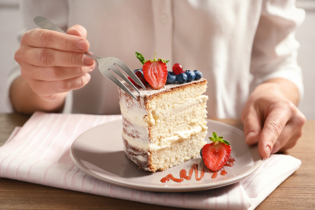 A slice of layered sponge cake topped with strawberries and blueberries