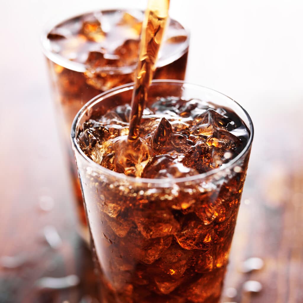 A sparkling soft drink is poured over ice, illustrating refreshing clean label beverage production with naturally derived malt ingredients.