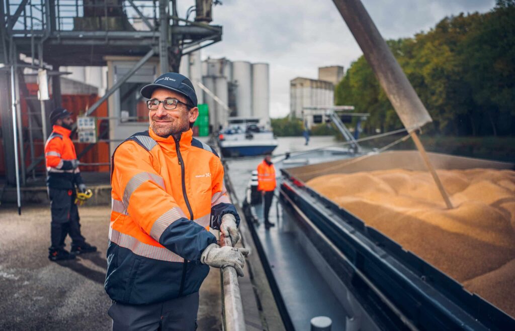A Soufflet malt employee oversees the loading of barley from a vessel into the malt facility, demonstrating a sustainable malt supplier committed to responsible raw material sourcing.