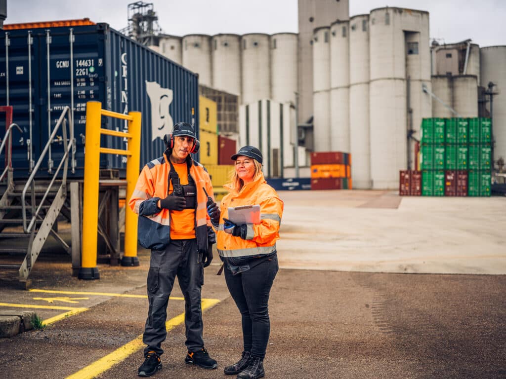 Two logistics colleagues discuss operations at malt storage site.